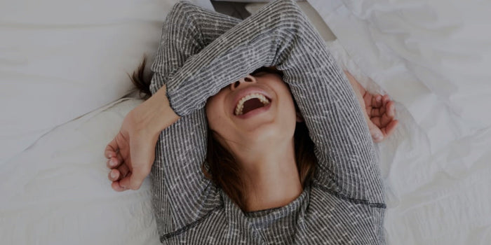 Een vrouw lacht ontspannen op bed